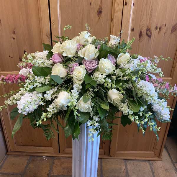 Large white and blush rose arrangement in a tall pedestal vase