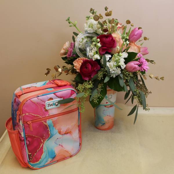 Mixed bouquet in a painted vase beside a colorful lunch bag