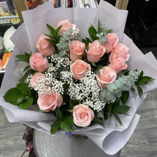 Bouquet of pink roses with white filler flowers wrapped in white paper