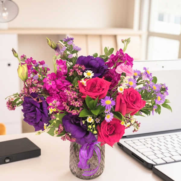 Bright mixed bouquet of pink, purple, and white flowers in a glass vase