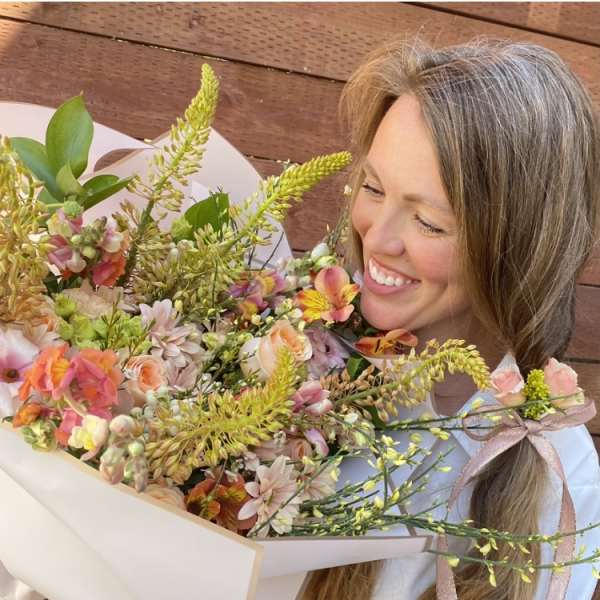 Woman holding a pastel mixed flower bouquet wrapped in white paper