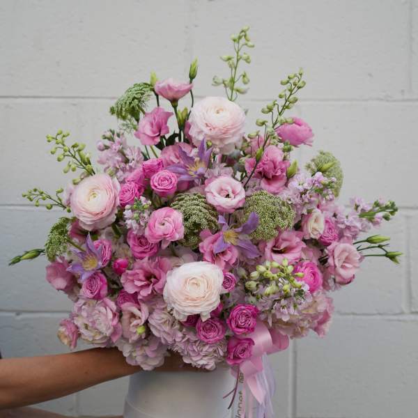Pink and white mixed flower bouquet in a white vase with ribbon