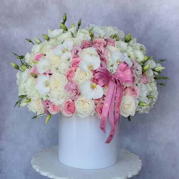 Pink and white rose arrangement in a white box with a ribbon bow
