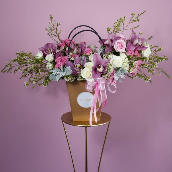 Pink and white flower arrangement in a brown handled box with ribbon