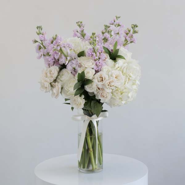 White and blush bouquet in a clear glass vase with a ribbon