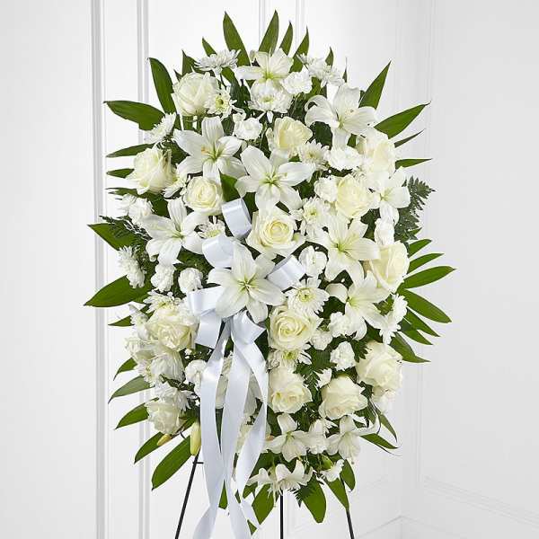 White floral standing spray with roses and lilies on an easel