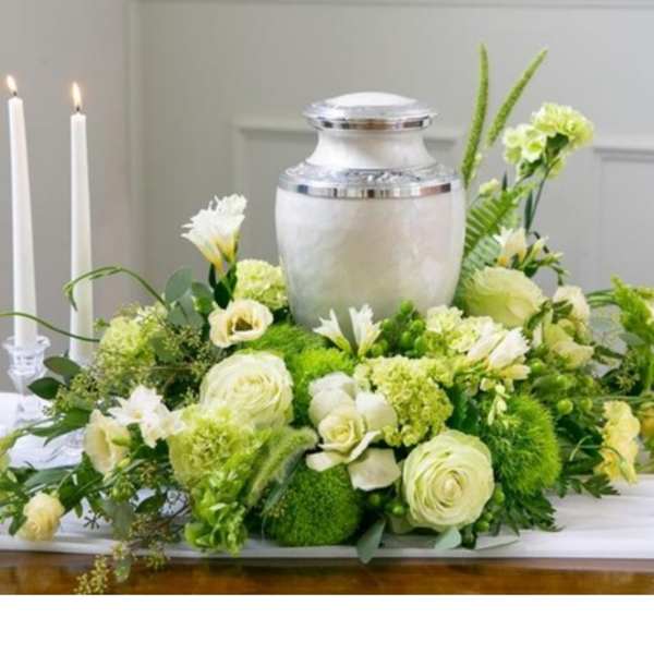 Green and white funeral floral arrangement with an urn centerpiece