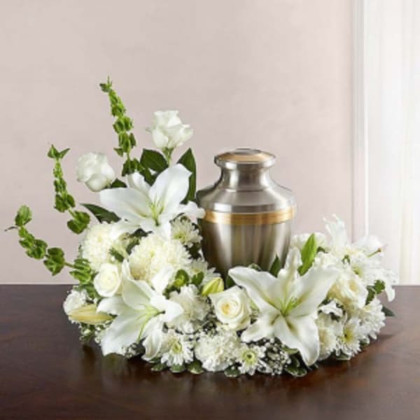 White floral wreath around a silver urn on a table