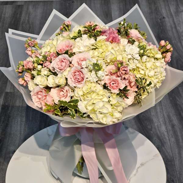 Bouquet of pink and white roses with hydrangeas wrapped in translucent paper