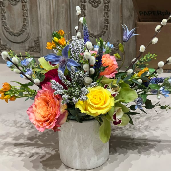 Colorful bouquet of roses and mixed flowers in a white vase