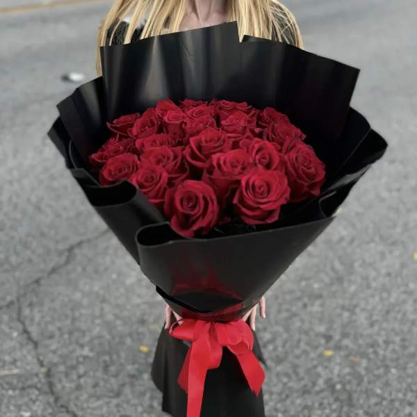 Bouquet of red roses wrapped in black paper with a red ribbon