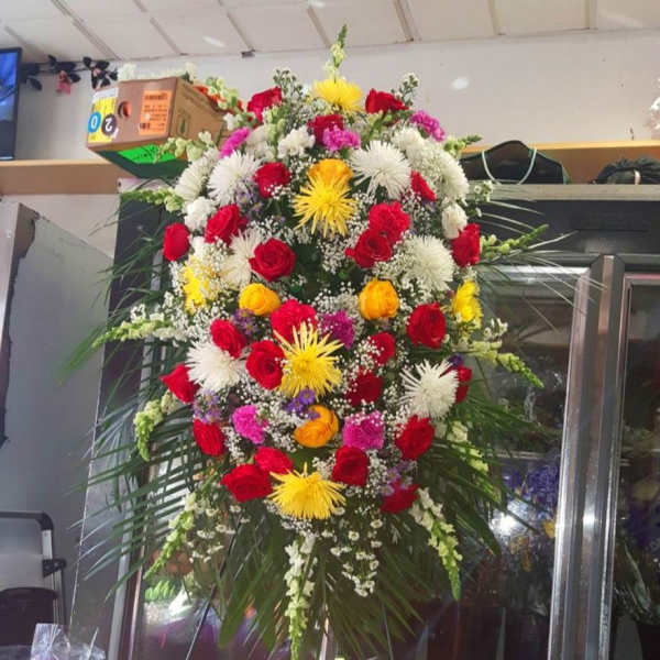 Large standing floral spray with red, white, yellow, and pink flowers