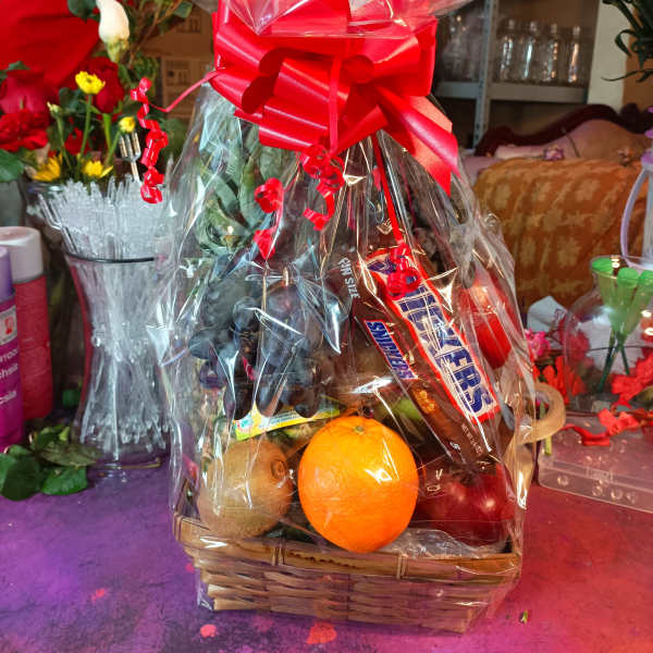 Gift basket with fruit and candy wrapped in clear cellophane and a red bow