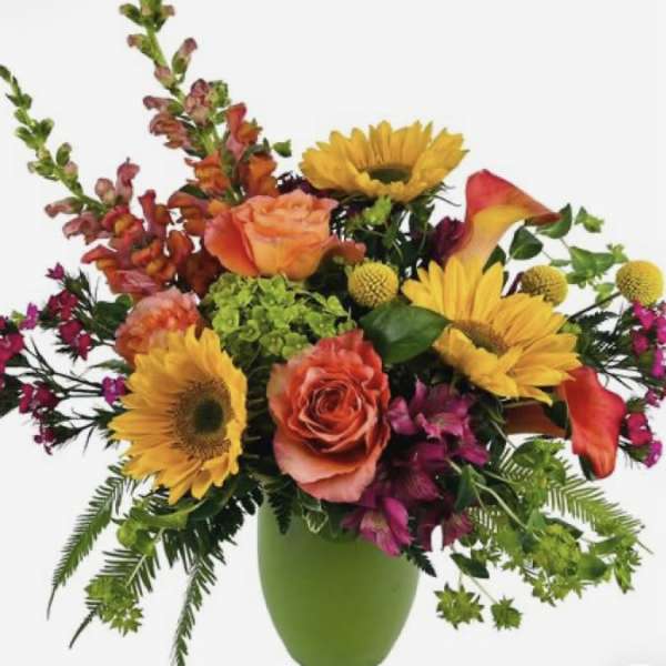 Mixed bouquet with sunflowers, roses, and calla lilies in a green vase