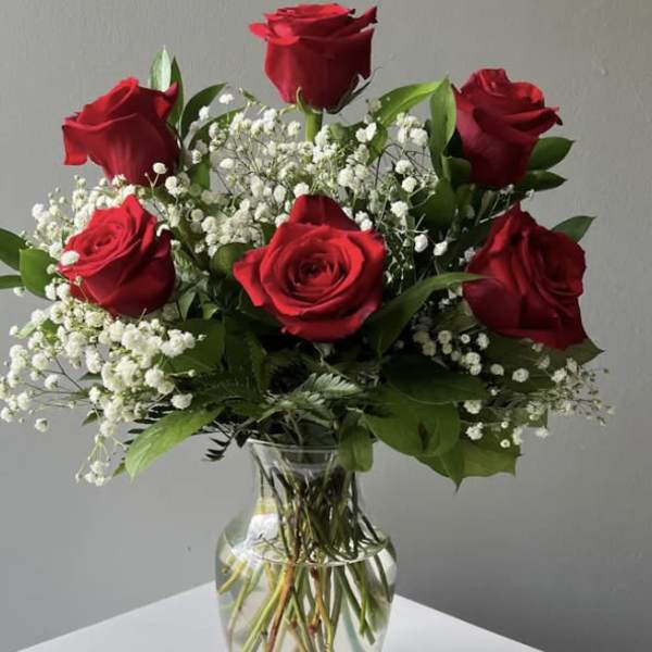Red roses and baby's breath arranged in a clear glass vase