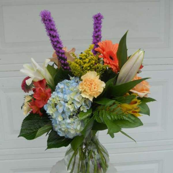 Mixed bouquet in a clear glass vase with hydrangea, lilies, and gerbera daisies