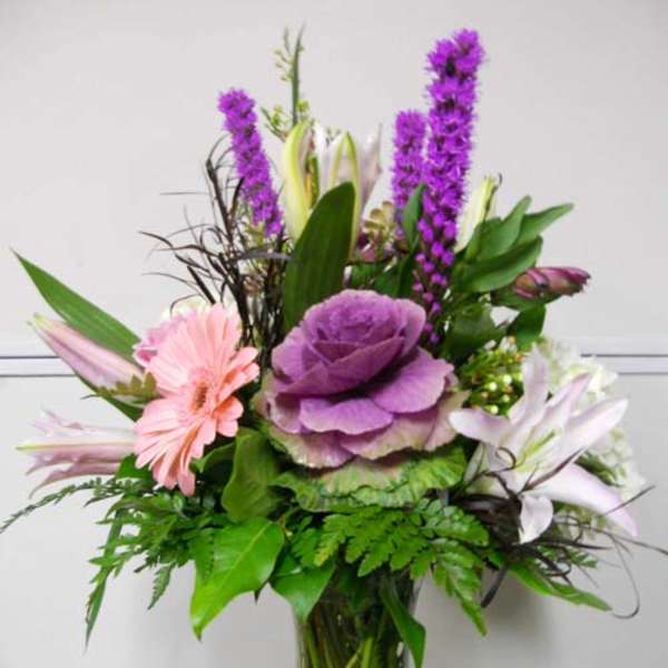 Mixed bouquet with purple, pink, and white flowers in a glass vase