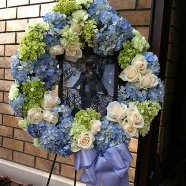Blue and green floral wreath with cream roses on a stand