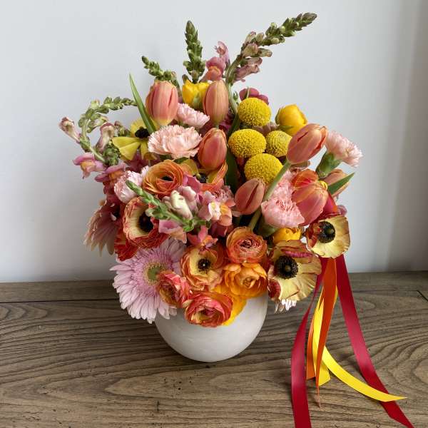 Colorful bouquet in a white vase with ribbon tails