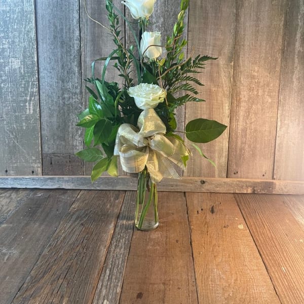 Tall white rose arrangement in a clear glass vase with a gold ribbon