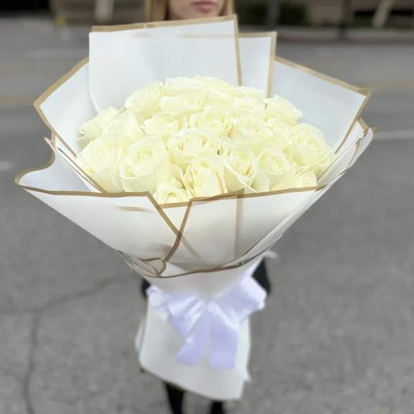 Bouquet of white roses wrapped in white paper with a ribbon