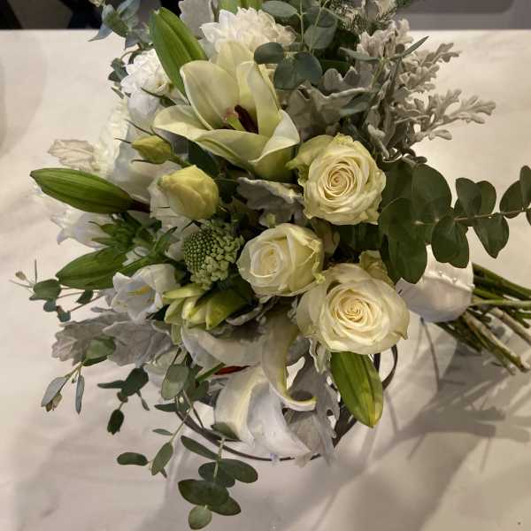 White roses and lilies arranged with eucalyptus in a bouquet
