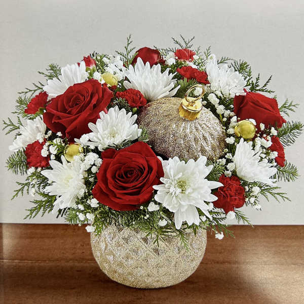 Red roses and white daisies arranged in a glittery gold vase with an ornament