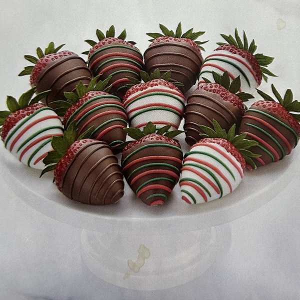 Plate of chocolate-covered strawberries with red, green, and white drizzle