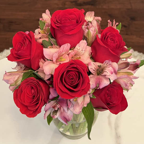 Red roses and pink alstroemeria in a clear glass vase