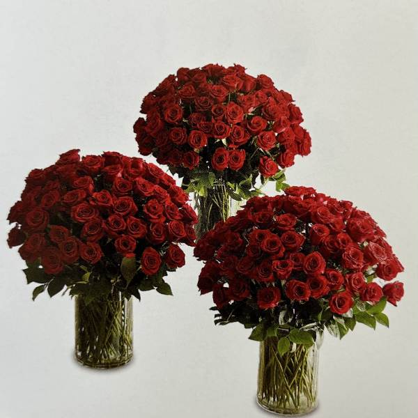 Three red rose arrangements in clear glass vases