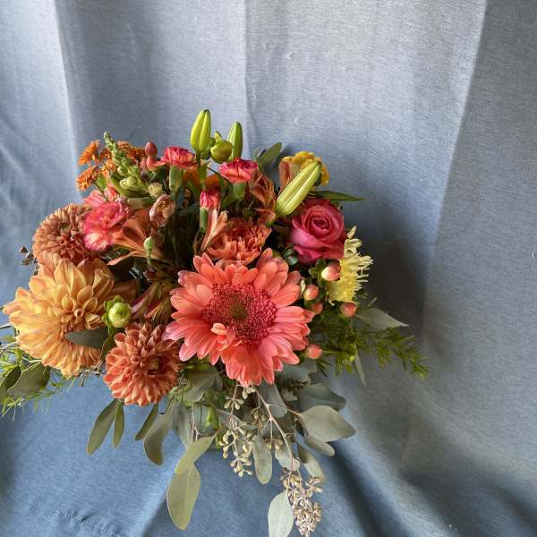 Mixed bouquet of pink, orange, and yellow flowers with greenery