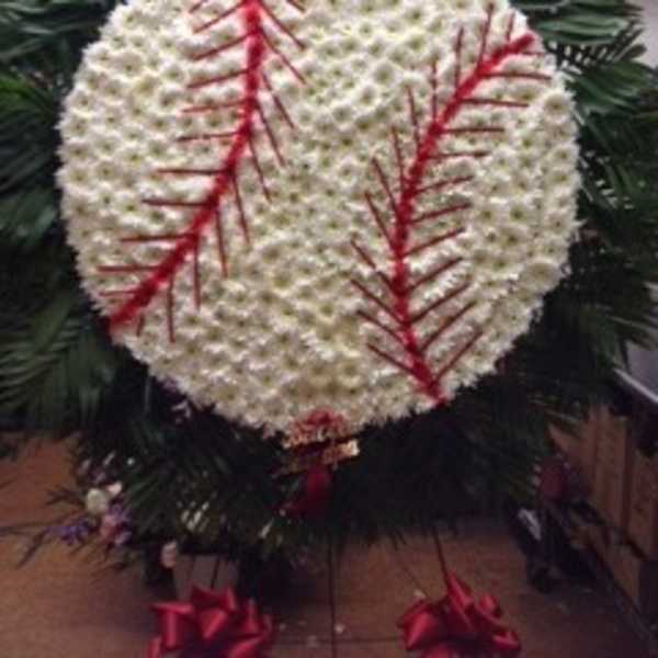 White floral funeral wreath with red accents and dark greenery