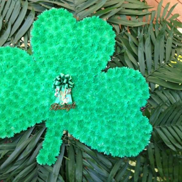 Green shamrock-shaped floral display with a ribbon centerpiece