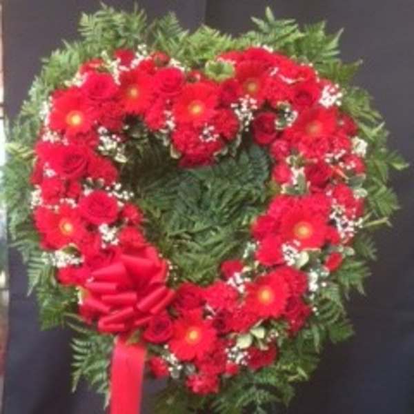 Heart-shaped red floral wreath with a ribbon bow