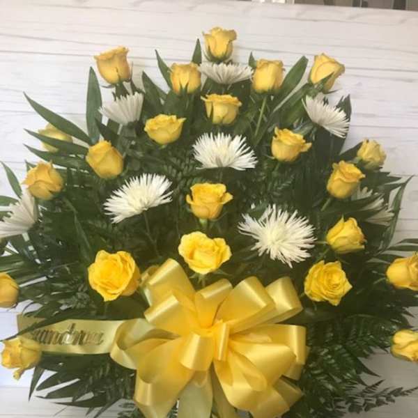 Yellow roses and white spider mums in a round arrangement with a yellow bow