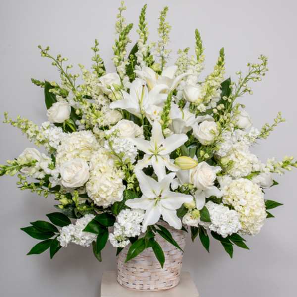 White lilies and roses in a woven basket arrangement