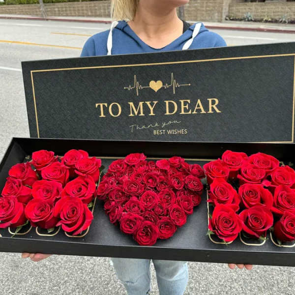 Black gift box with red roses arranged in a heart shape