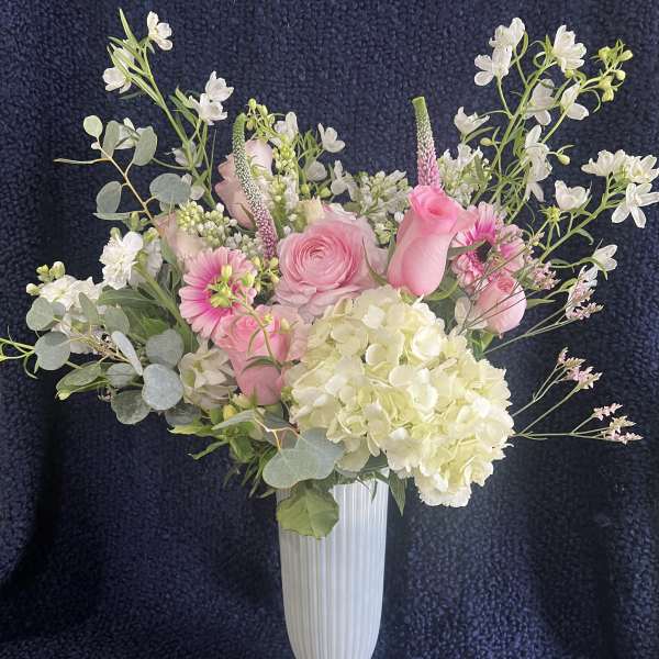 Pink and white floral arrangement in a tall white vase