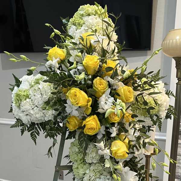 Tall standing floral cross with yellow roses and white hydrangeas