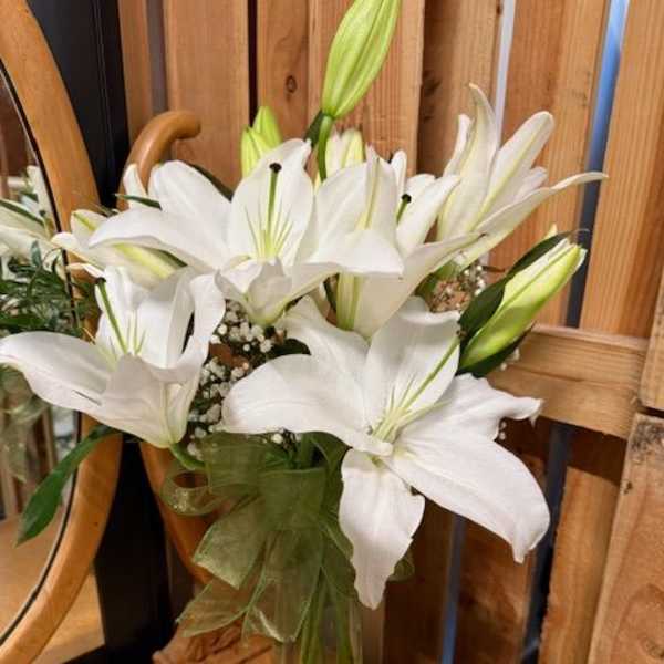 White lilies arranged in a clear glass vase