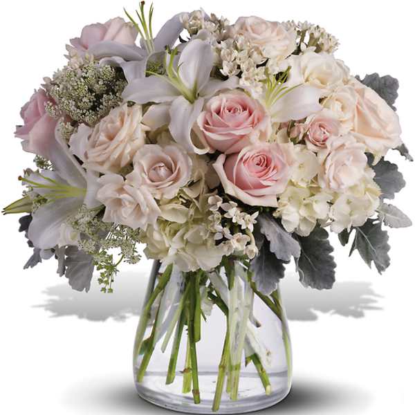 Bouquet of pale pink and white roses with lilies in a clear glass vase
