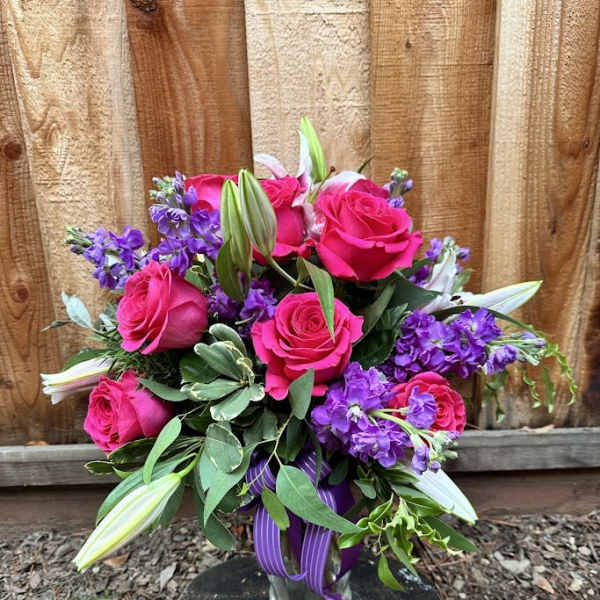 Bouquet of hot pink roses and purple flowers in a glass vase