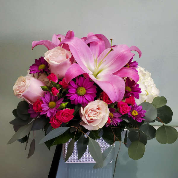 Pink lilies and roses arranged in a square vase
