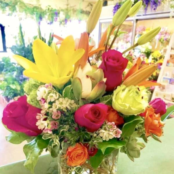 Colorful bouquet of lilies and roses in a clear glass vase