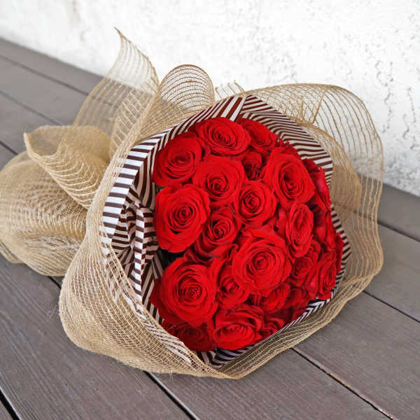 Bouquet of red roses wrapped in striped paper and burlap mesh
