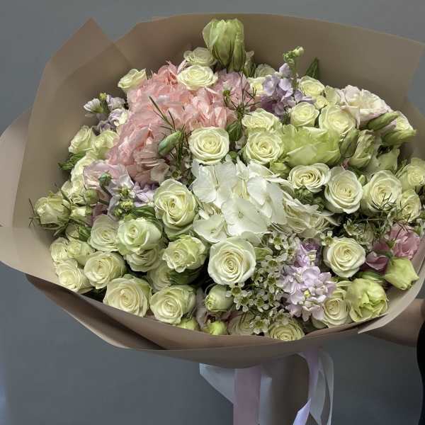 Bouquet of cream roses, pink blooms, and white flowers wrapped in tan paper