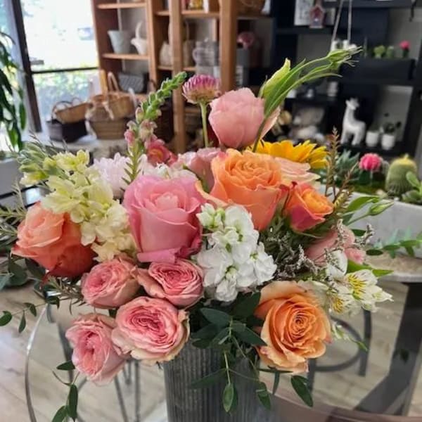 Mixed pink, peach, and white flower arrangement in a gray vase