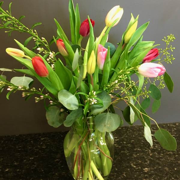 Bouquet of multicolored tulips in a clear glass vase