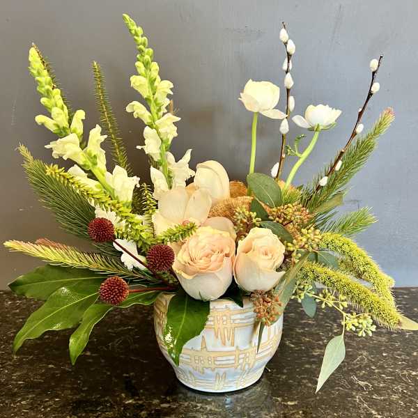 Mixed floral arrangement in a patterned ceramic vase with pale roses and white blooms