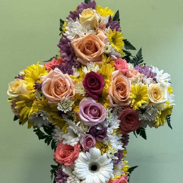 Cross-shaped floral arrangement with roses and daisies on a stand